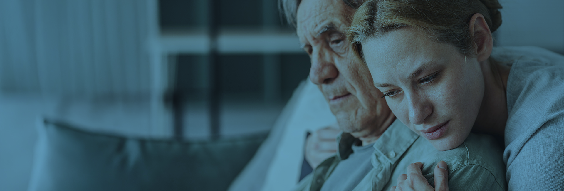 blue toned image of a middle aged woman hugging her father